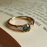 Round teal sapphire and pear diamond three stone engagement ring with gold setting