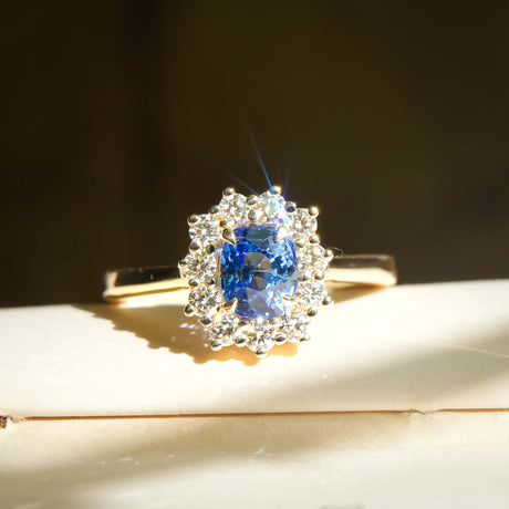 Royal blue sapphire and diamond cluster halo engagement ring in yellow gold setting