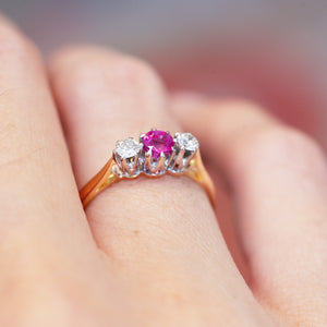 Ruby and diamond three-stone ring showing raised vintage setting and gold band.
