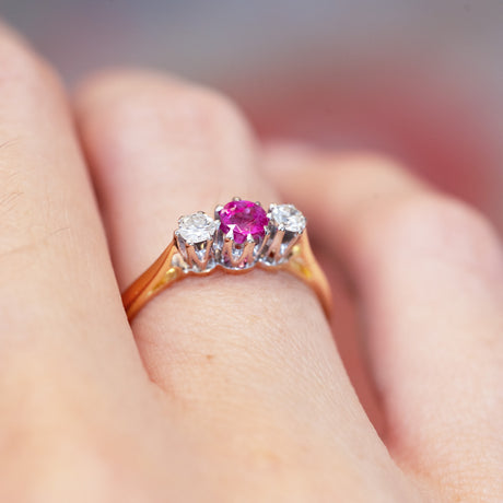 Ruby and diamond three-stone ring showing raised vintage setting and gold band.