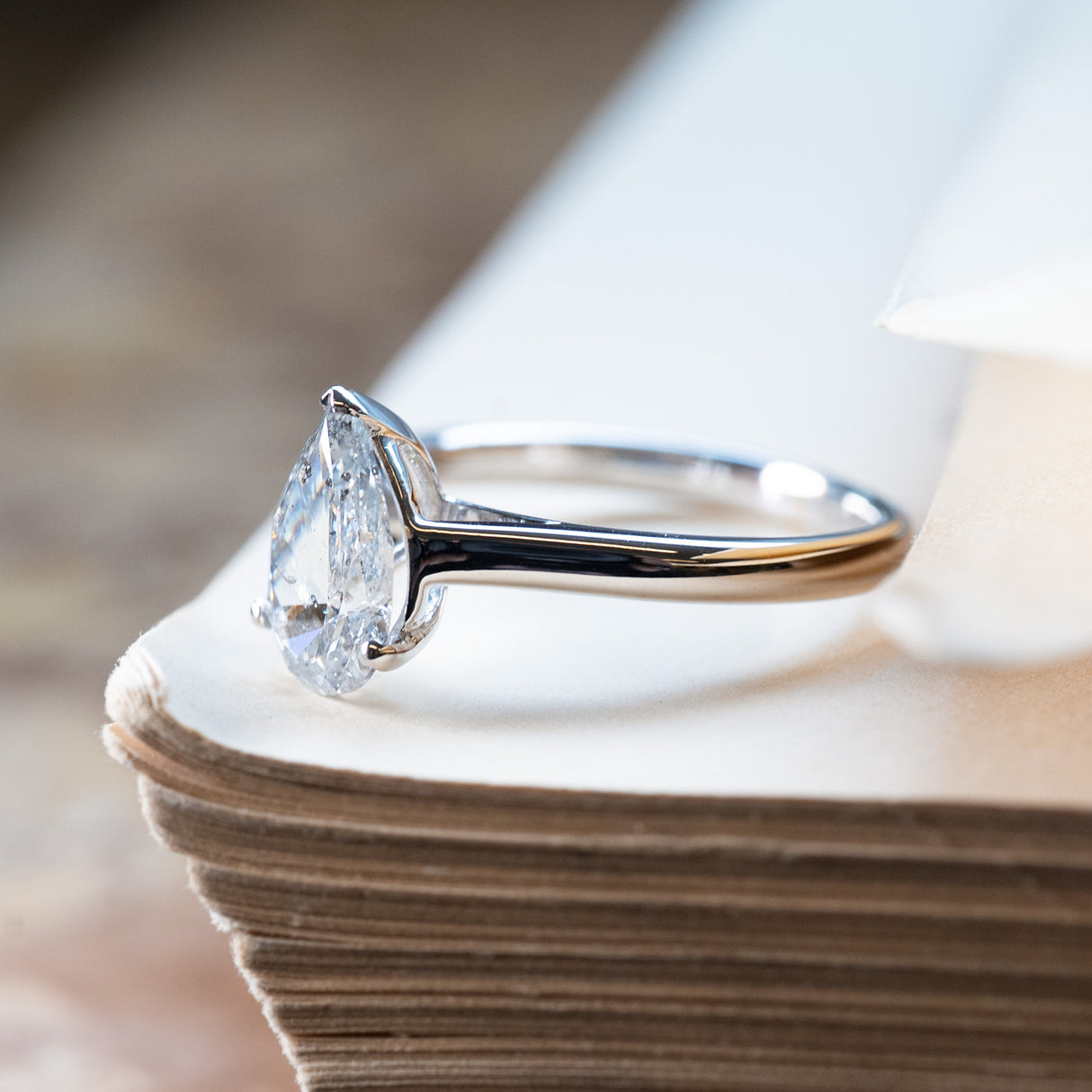Vintage salt and pepper diamond solitaire ring with pear-shaped diamond in elevated claw setting.