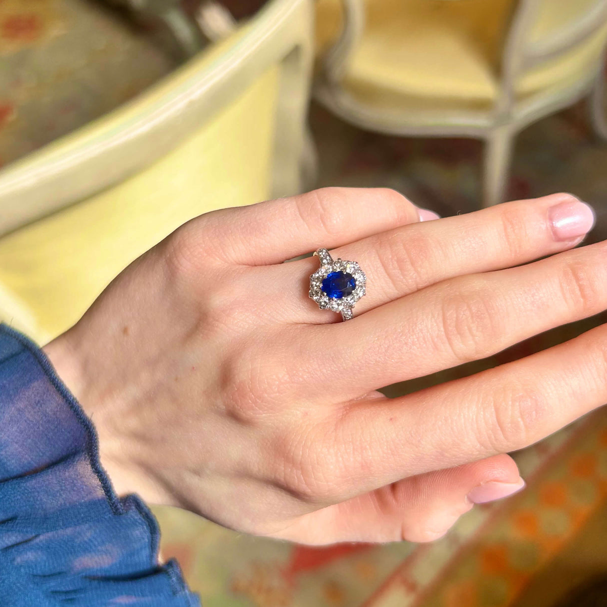 Sapphire and diamong cluster ring worn on hand in relaxed pose