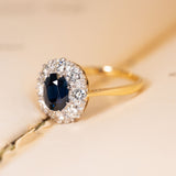 Vintage 1960s sapphire and diamond cluster ring showcasing an oval blue sapphire framed by a sparkling cluster of brilliant-cut diamonds.