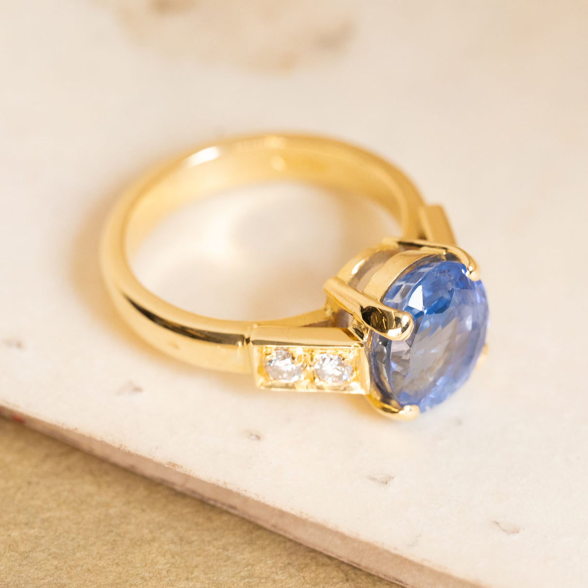 Vintage 1990s blue sapphire and diamond engagement ring with an oval-cut sapphire and channel-set diamond shoulders in yellow gold.
