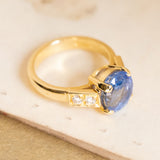 Vintage 1990s blue sapphire and diamond engagement ring with an oval-cut sapphire and channel-set diamond shoulders in yellow gold.