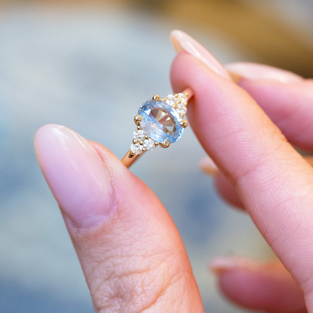 Pale blue sapphire and diamond cluster tre-foil engagement ring with oval sapphire and brilliant-cut diamonds.