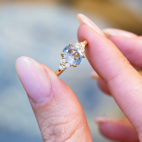 Pale blue sapphire and diamond cluster tre-foil engagement ring with oval sapphire and brilliant-cut diamonds.