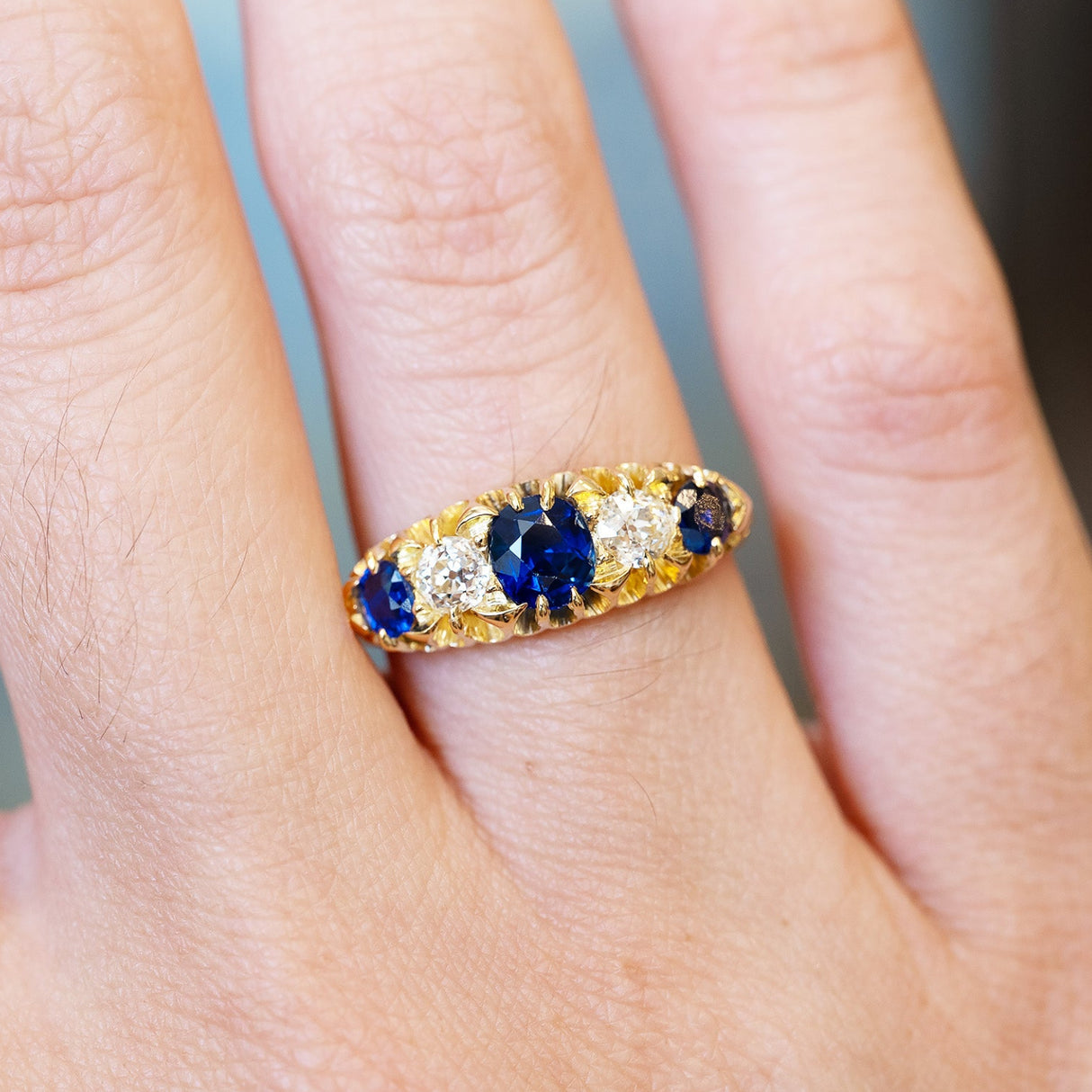Sapphire and old mine cut diamond five stone ring close detail showing central blue stone.