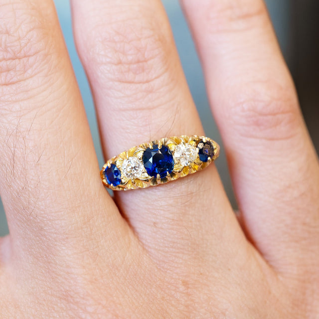 Sapphire and old mine cut diamond five stone ring close detail showing central blue stone.