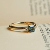 Square cut teal sapphire engagement ring with diamond three stone setting