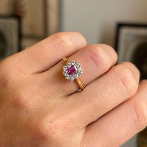Close-up of an antique-inspired yellow gold cluster ring showcasing a step-cut pinkish-red ruby encircled by brilliant diamonds, highlighting colour, sparkle and fine craftsmanship.