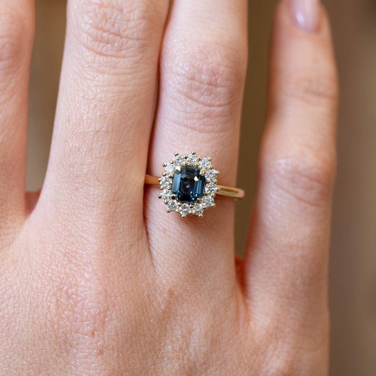 Close detail of teal sapphire and diamond cluster engagement ring with diamond halo.