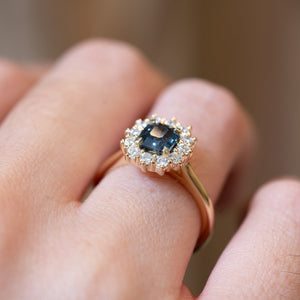 Detailed view of teal sapphire and diamond cluster engagement ring showing gemstone setting.