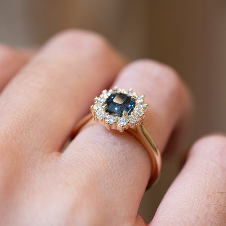 Detailed view of teal sapphire and diamond cluster engagement ring showing gemstone setting.