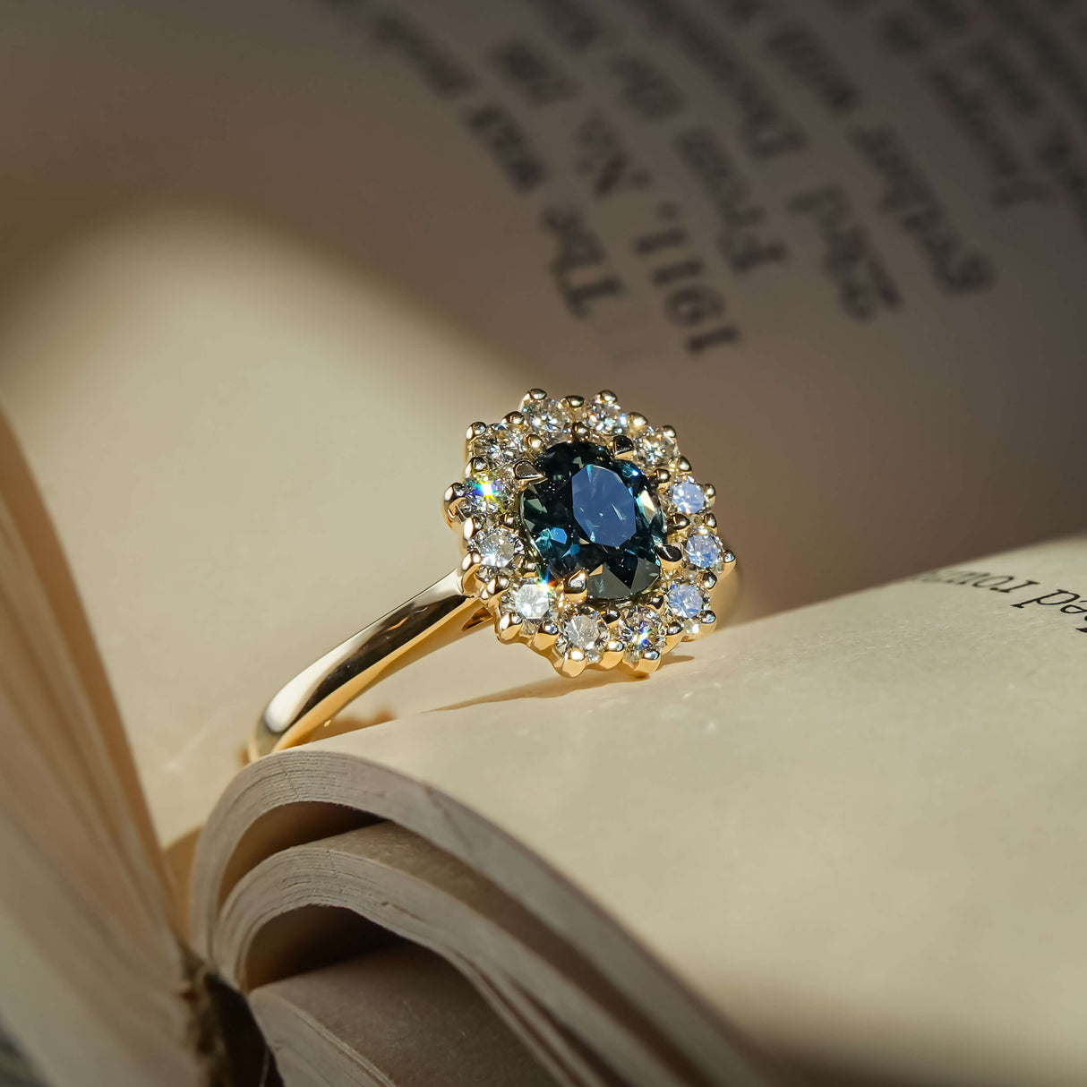 Teal sapphire ring with oval gemstone and diamond cluster halo in gold