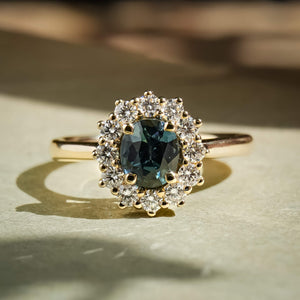 Teal sapphire center stone with diamond cluster halo engagement ring