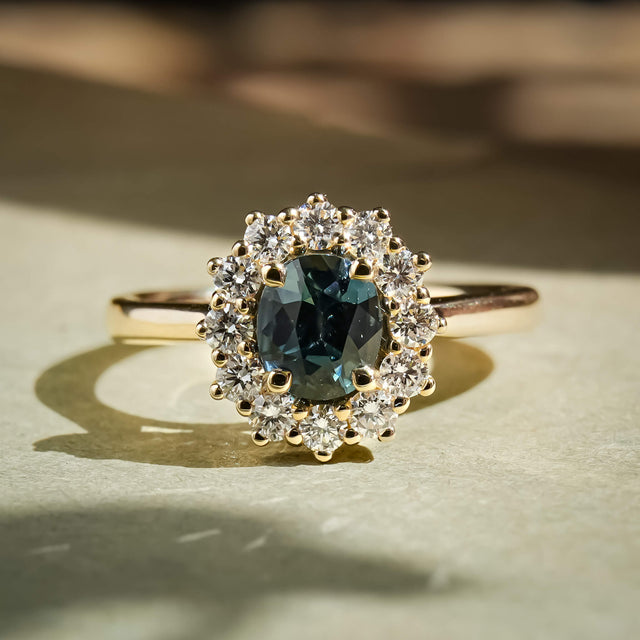 Teal sapphire center stone with diamond cluster halo engagement ring