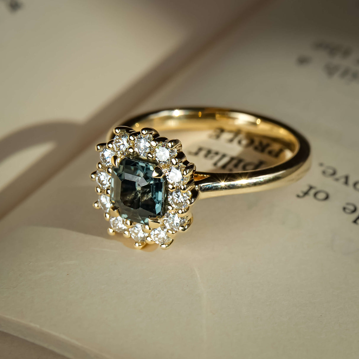 Teal sapphire engagement ring with oval gemstone and diamond cluster halo