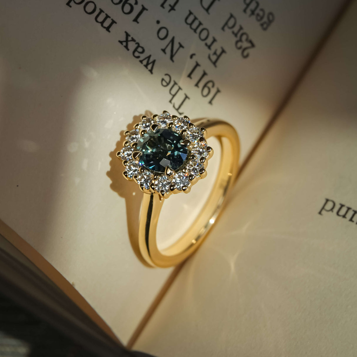 Teal sapphire engagement ring with oval gemstone and diamond cluster halo