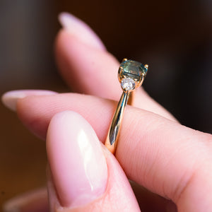 Teal sapphire and diamond three-stone engagement ring with emerald-cut teal sapphire and diamond side stones.