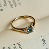 Teal sapphire engagement ring with diamond three stone setting in yellow gold