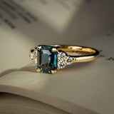 Teal sapphire ring with emerald cut gemstone and diamond trefoil cluster