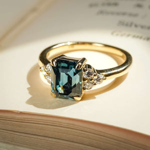 Teal sapphire ring with emerald cut gemstone and diamond trefoil cluster design