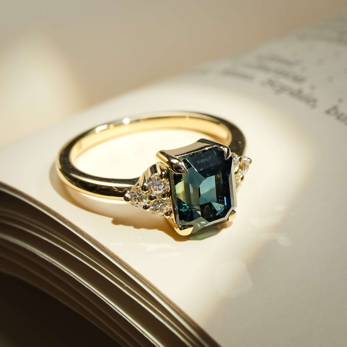 Teal sapphire ring with emerald cut gemstone and diamond trefoil cluster