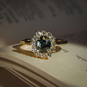 Teal sapphire engagement ring with oval gemstone and diamond halo cluster