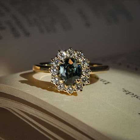 Teal sapphire engagement ring with oval gemstone and diamond halo cluster