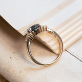 Teal sapphire and diamond cluster tre-foil engagement ring with open gallery setting and polished gold band.