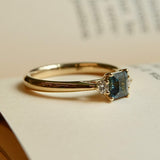 Teal sapphire centre stone engagement ring with diamond three stone design