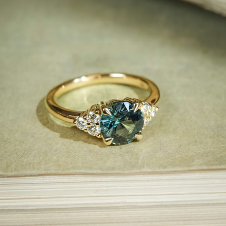 Teal sapphire trefoil cluster engagement ring in yellow gold with diamond side stones