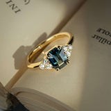 Teal sapphire ring with emerald cut gemstone and diamond trefoil cluster in gold
