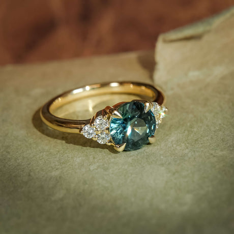 Classic teal sapphire engagement ring with trefoil diamond side stones