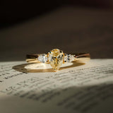 tinted yellow pear diamond three stone ring with diamond accents in yellow gold