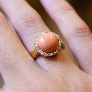 Victorian angel skin coral ring showing coral centre stone and diamond halo detail.