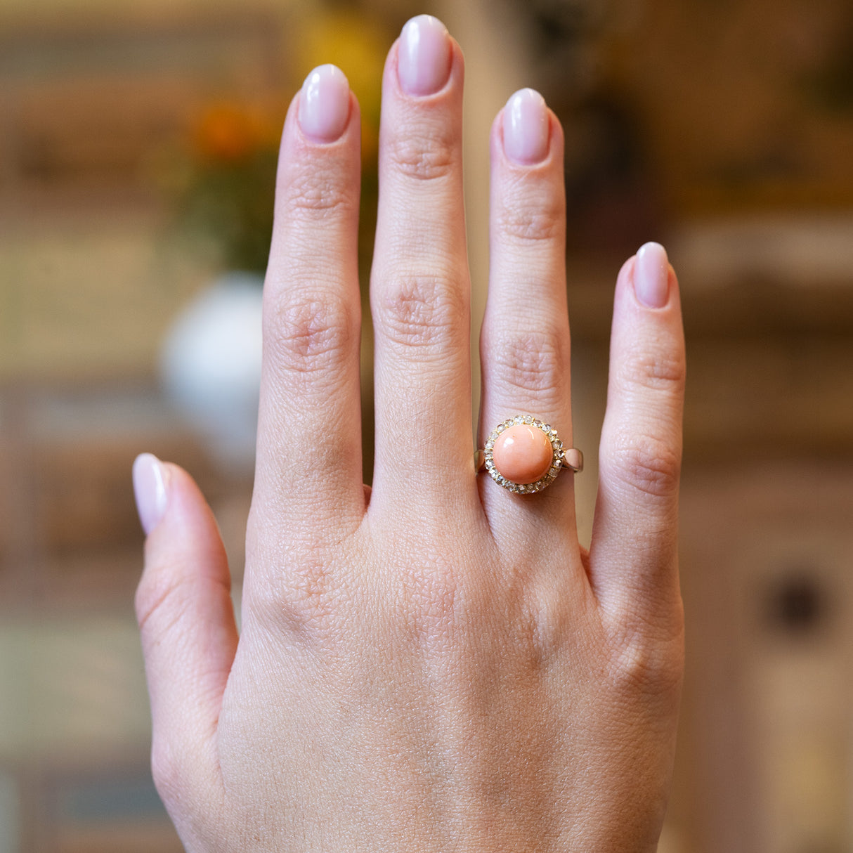 Victorian angel skin coral and diamond cluster ring worn on hand with soft pink manicure.