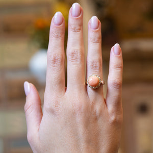 Victorian angel skin coral and diamond cluster ring worn on hand with soft pink manicure.