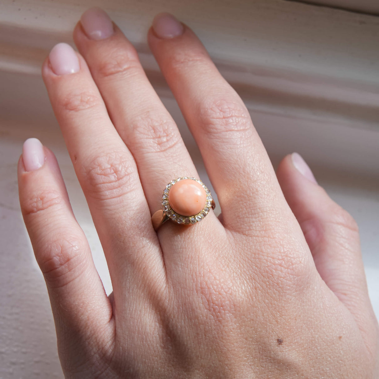Antique Victorian angel skin coral ring with diamond cluster setting on hand