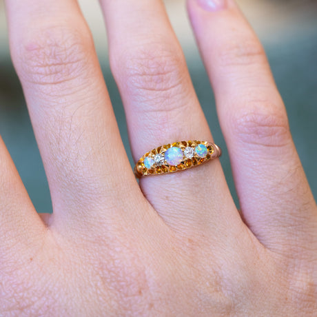 Antique opal and diamond five-stone ring with gold band and iridescent opals.