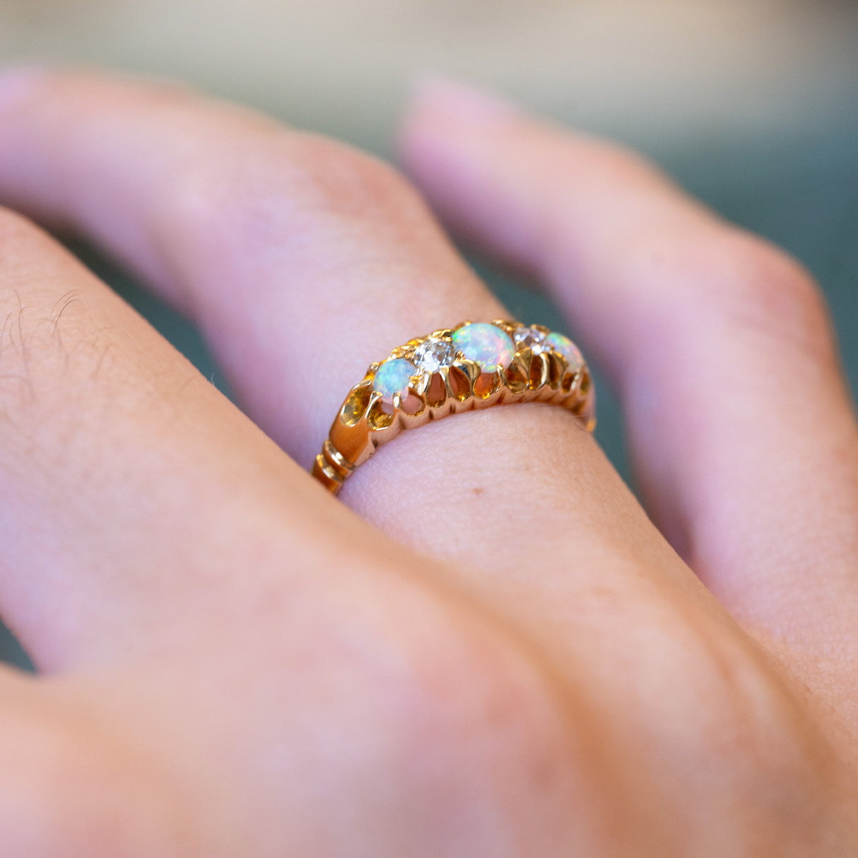 Antique late Victorian opal and diamond five-stone ring showing ornate gold setting.