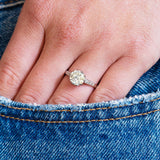 Close-up of a hand wearing a vintage diamond ring with a denim jeans pocket detail.