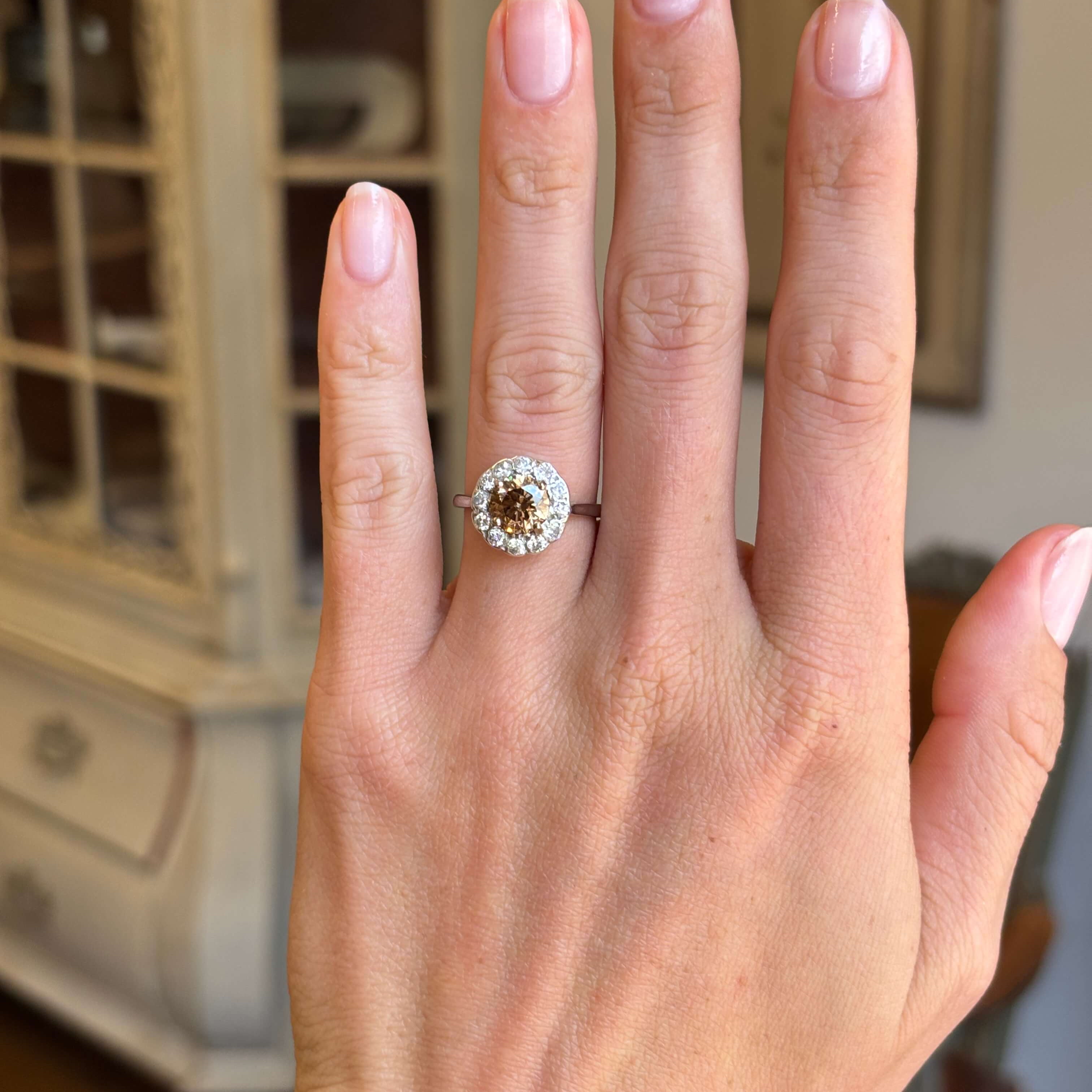 Vintage 1950s cinnamon brown diamond cluster engagement ring with a cinnamon brown diamond centre stone and diamond halo, displayed on a hand.