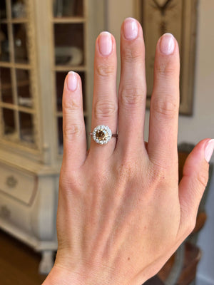 Vintage 1950s cinnamon brown diamond cluster engagement ring with a cinnamon brown diamond centre stone and diamond halo, displayed on a hand.