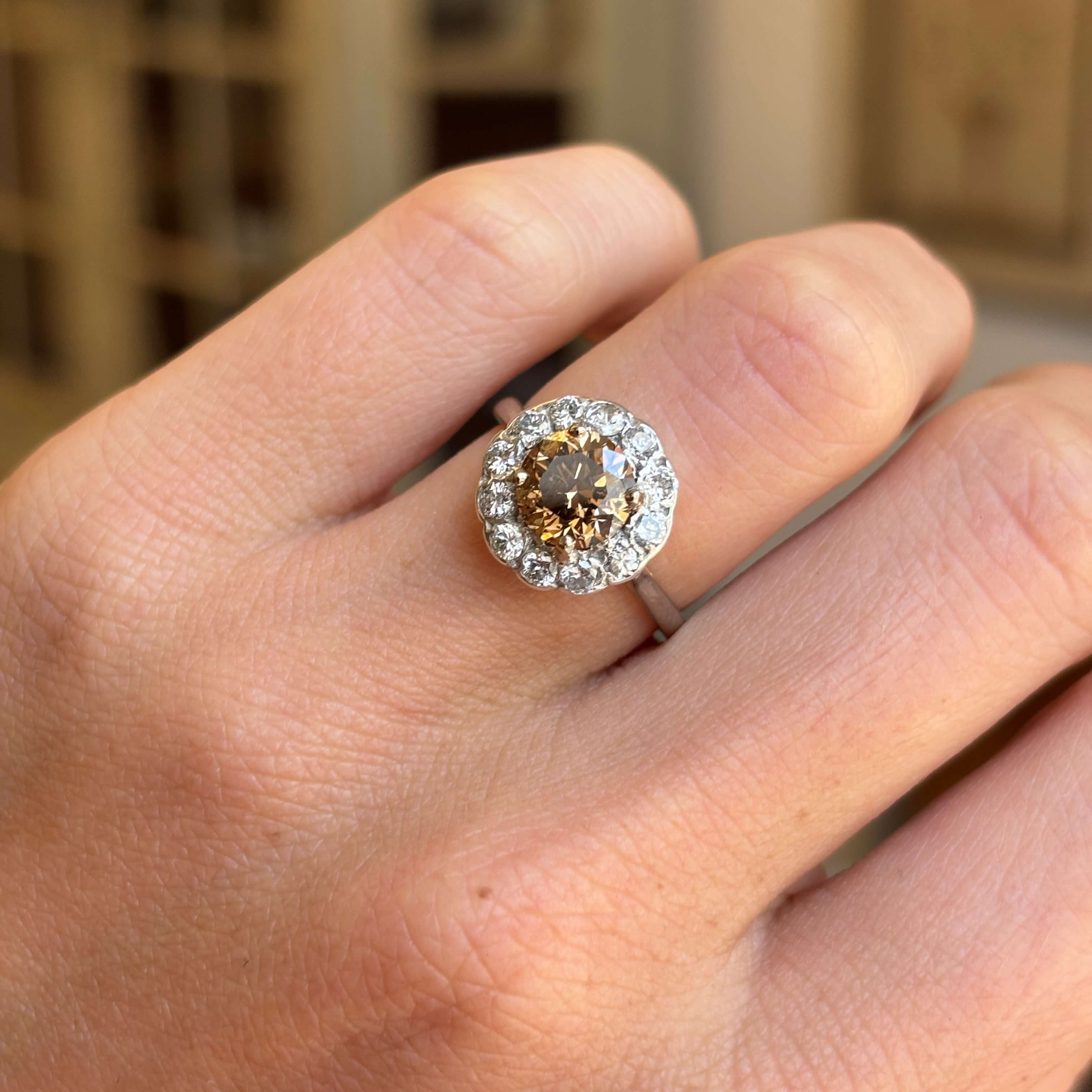 Vintage 1950s cinnamon brown diamond cluster engagement ring featuring a cinnamon brown diamond encircled by sparkling diamonds, worn on a hand.