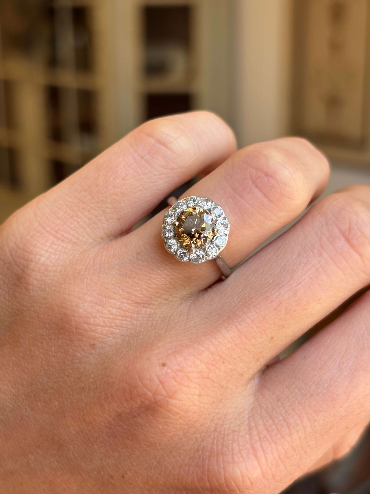 Vintage 1950s cinnamon brown diamond cluster engagement ring featuring a cinnamon brown diamond encircled by sparkling diamonds, worn on a hand.