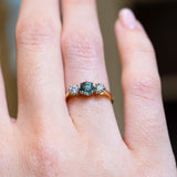 Close detail of vintage 1950s green sapphire and diamond three-stone engagement ring.