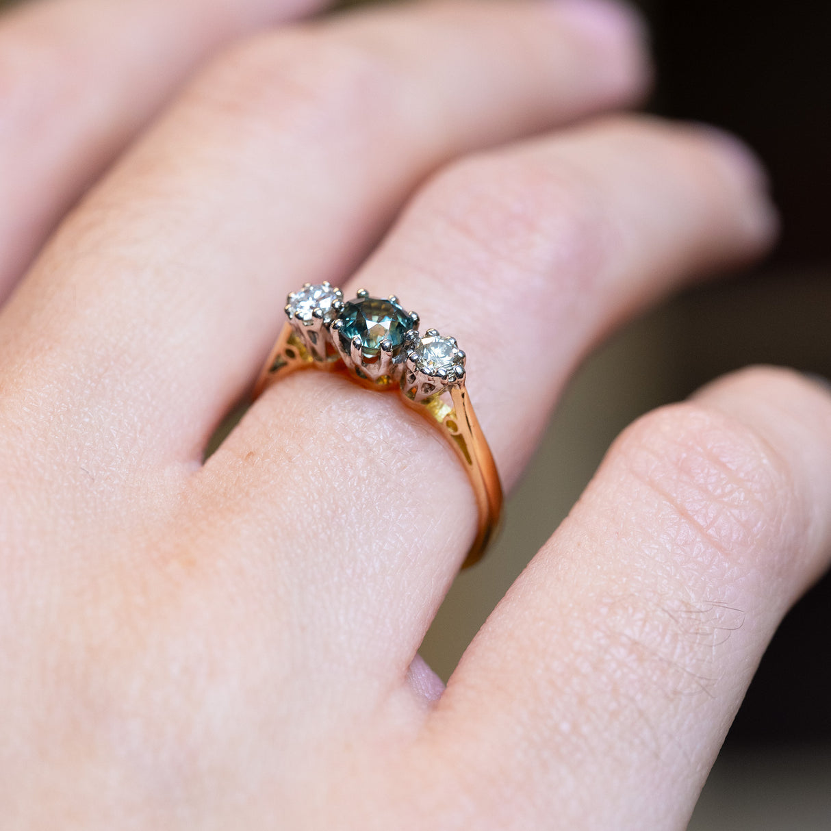 Detailed view of vintage 1950s green sapphire and diamond three-stone engagement ring showing gemstone setting.