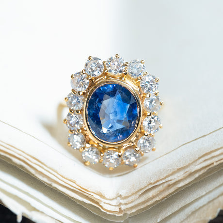 Vintage 1960s French sapphire and diamond cluster ring with oval blue sapphire surrounded by diamonds.